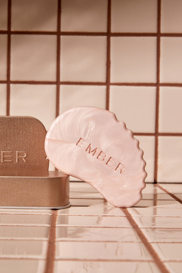The Sculpt & Glow Bar rests on its case in front of a tiled background