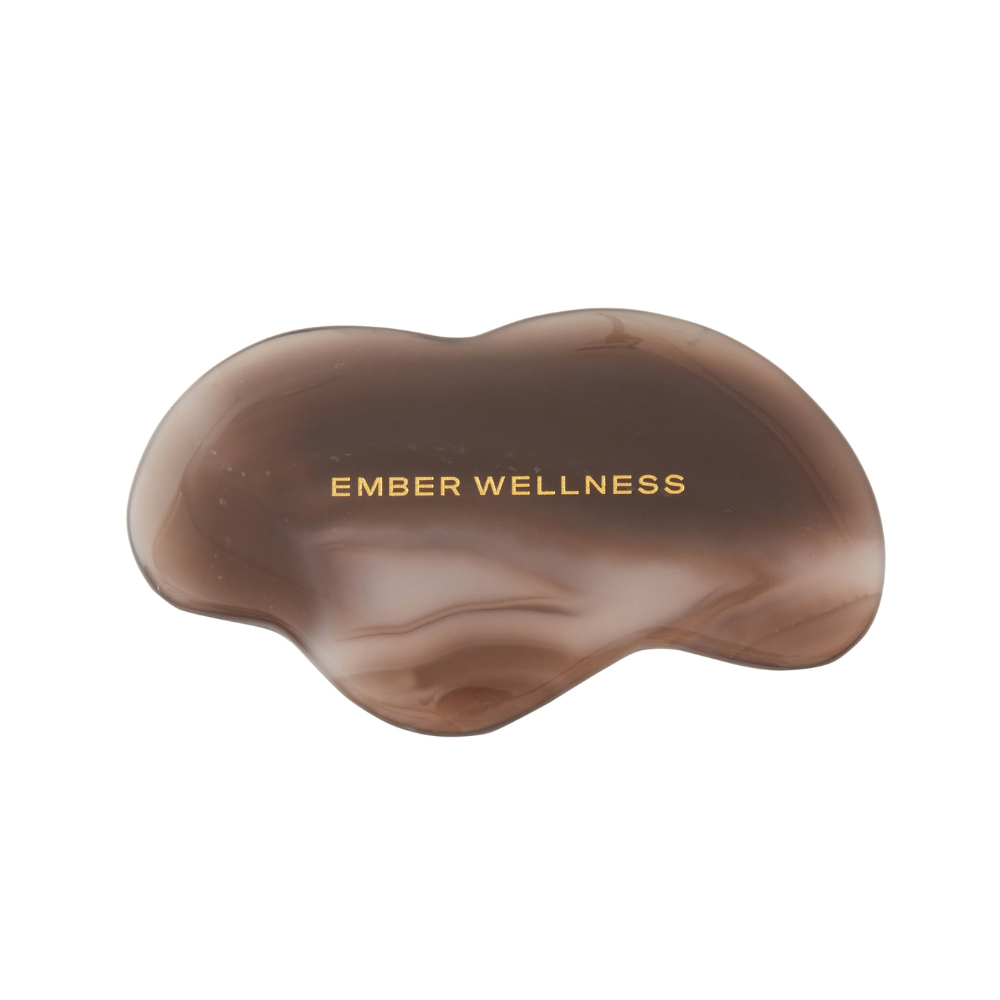 Brown handheld gua sha with 'Ember Wellness' branding on a white background